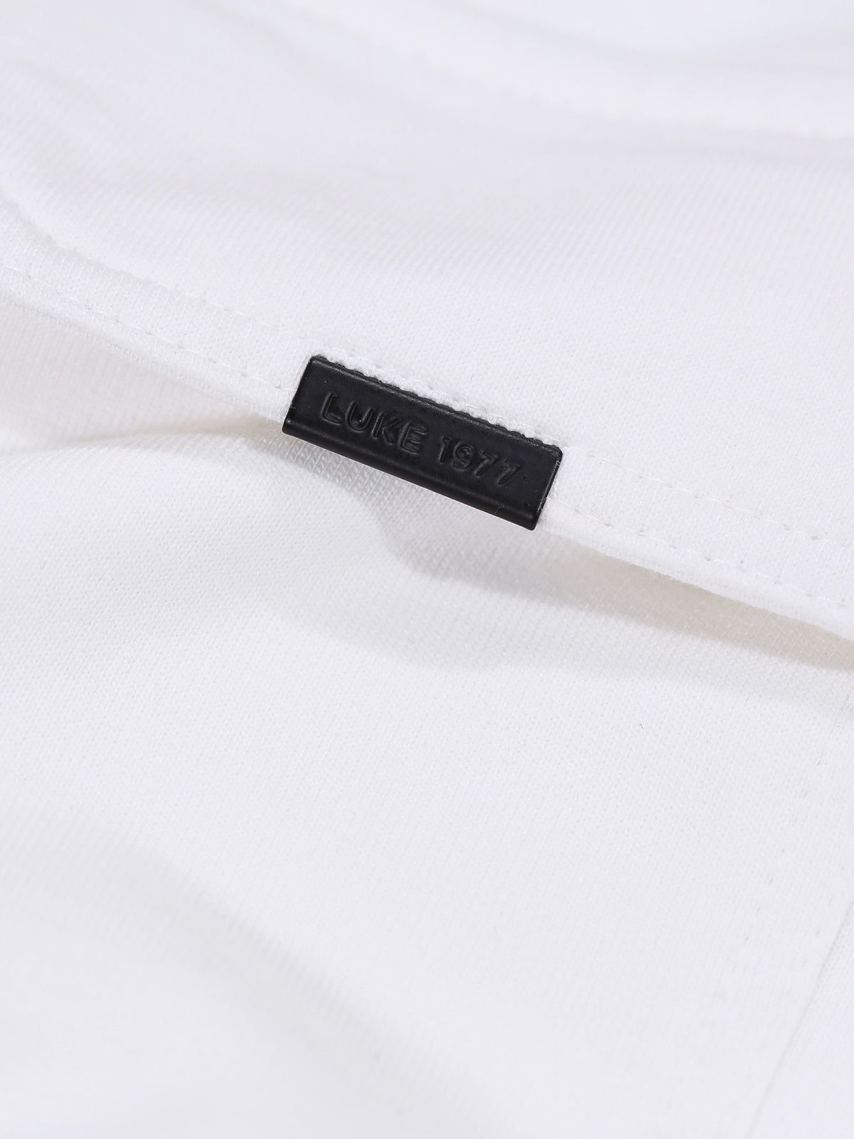 Close-up of chest pocket with LUKE 1977 branded metal clip on white Dragger t-shirt