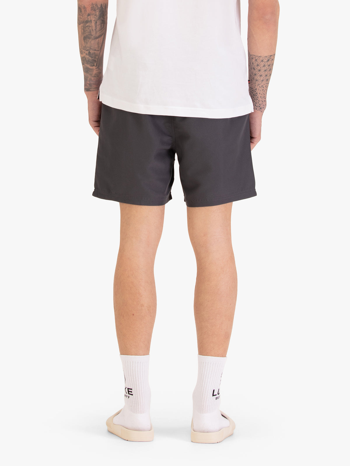 Men's grey swim shorts with drawstring waistband, worn by a model, back view