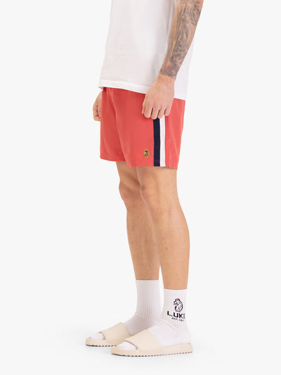 Men's red swim shorts with drawstring waistband, worn by a model, worn by a model, side view