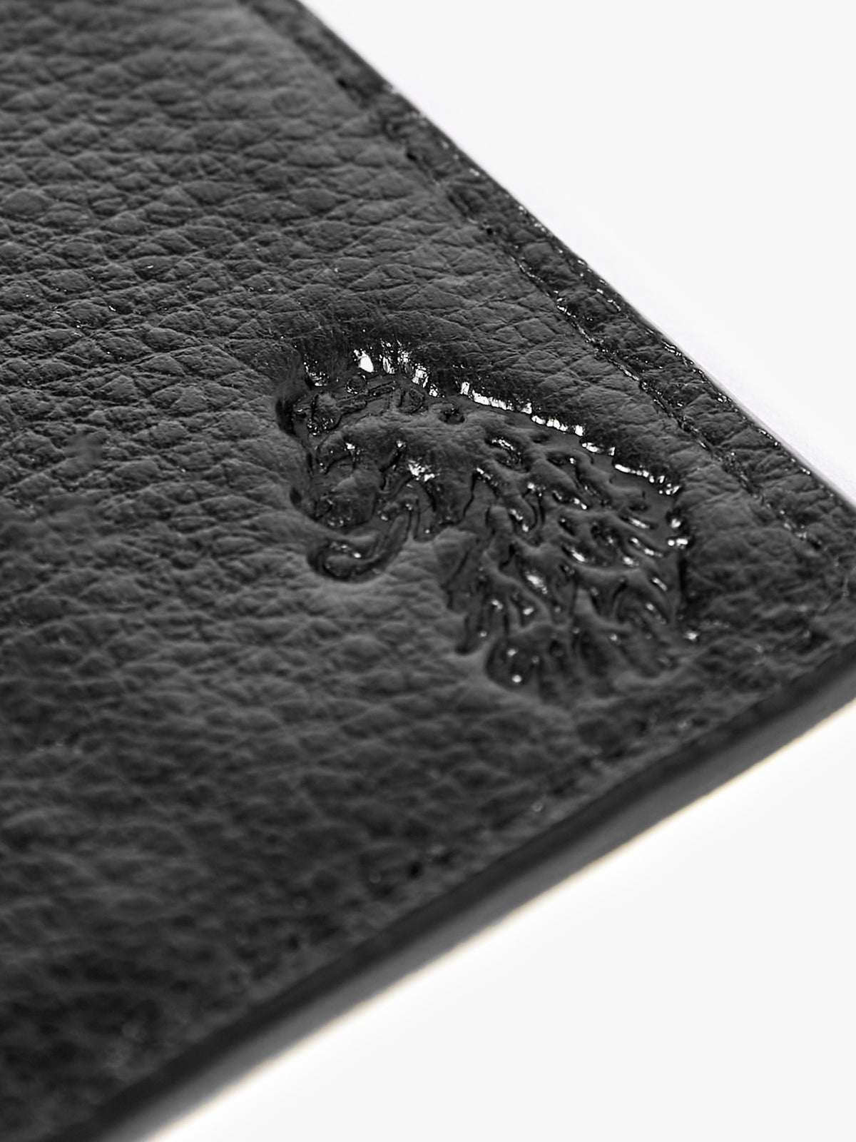 Close-up of debossed LUKE lion head on black Milled leather card holder