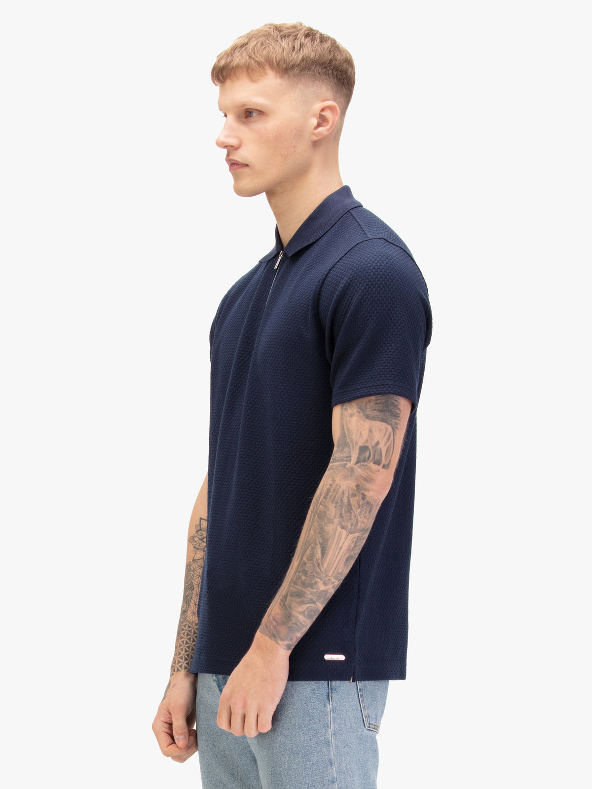 Men's navy polo shirt with zip collar, worn by model, side view