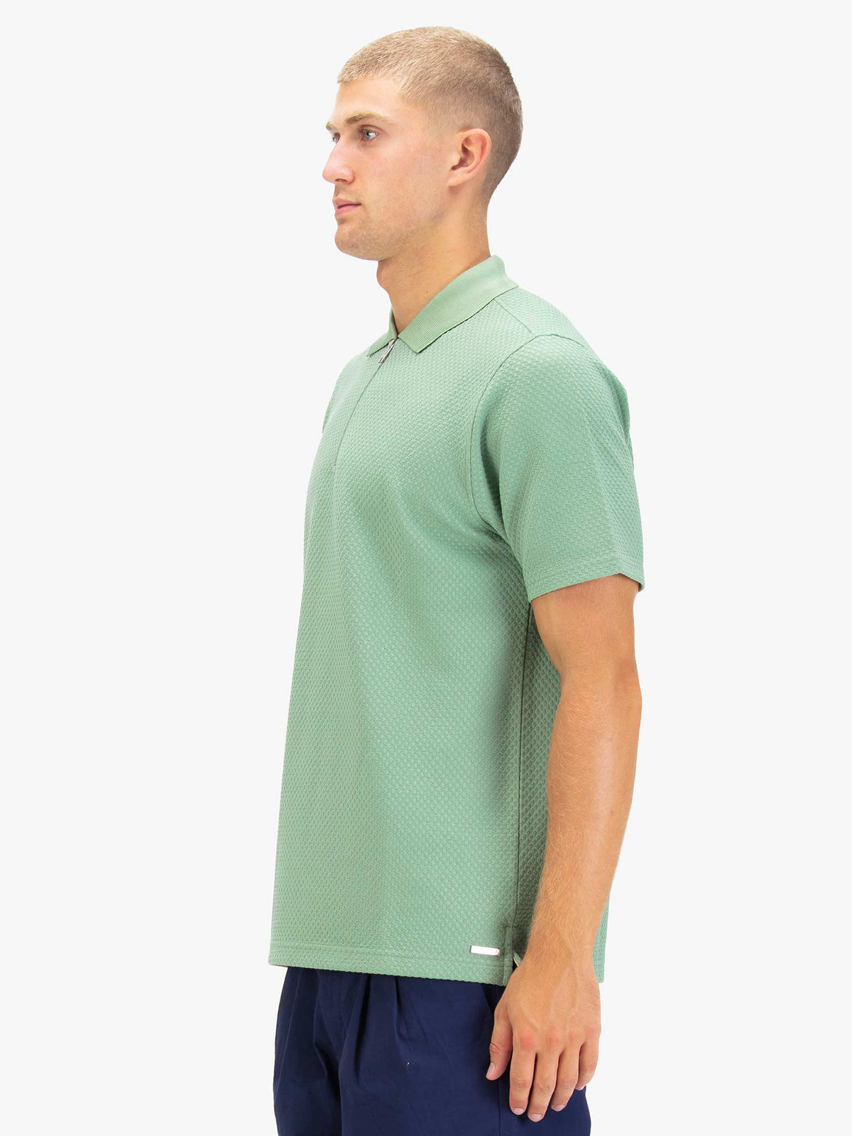 Men's green polo shirt with zip collar, worn by model, side view