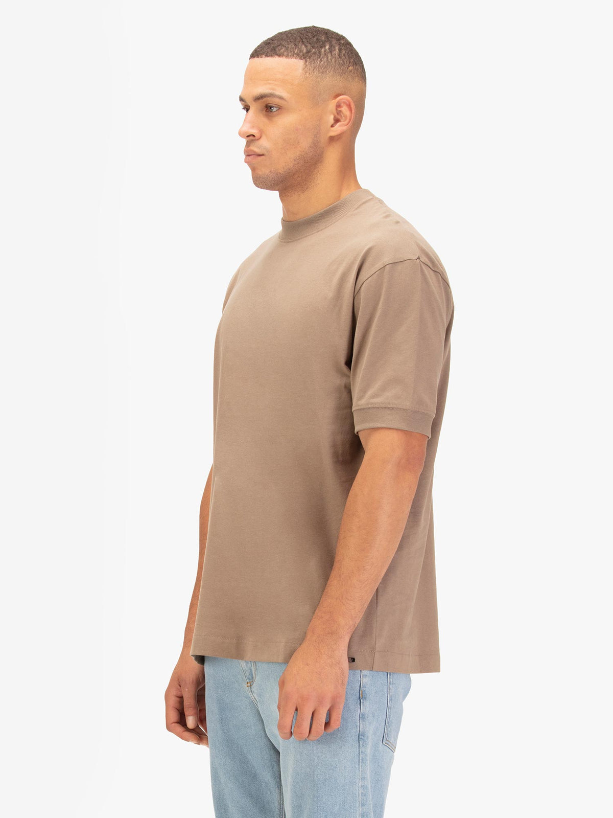 Men's relaxed-fit brown t-shirt with crew neck and short sleeves, worn by a model, side view