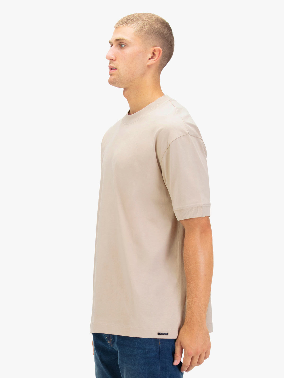 Men's relaxed-fit beige t-shirt with crew neck and short sleeves, worn by a model, side view