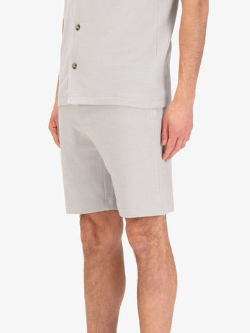 Men's grey shorts with drawstring waistband, worn by a model, side view