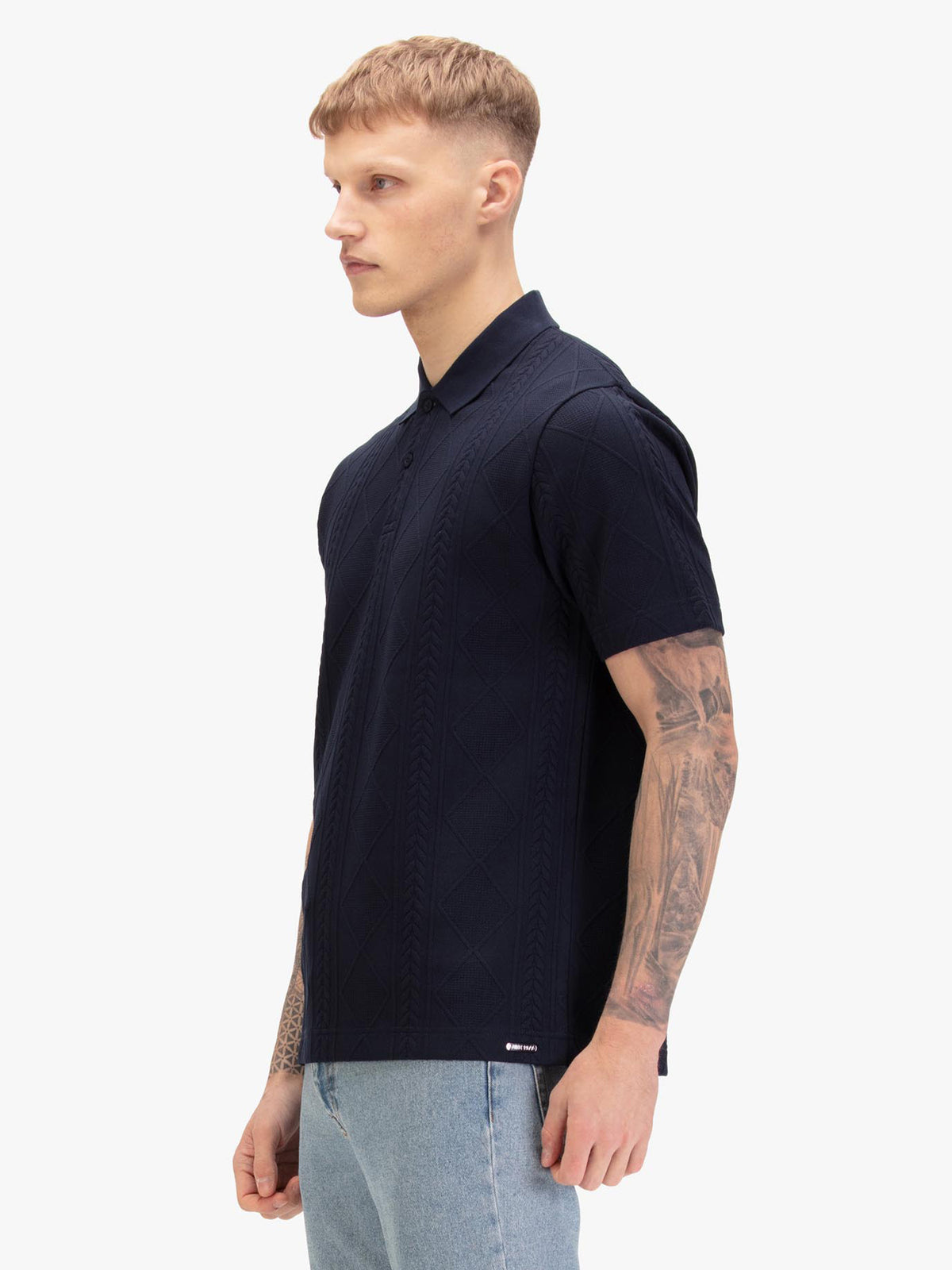 Men's navy polo shirt with polo collar, worn by a model, side view