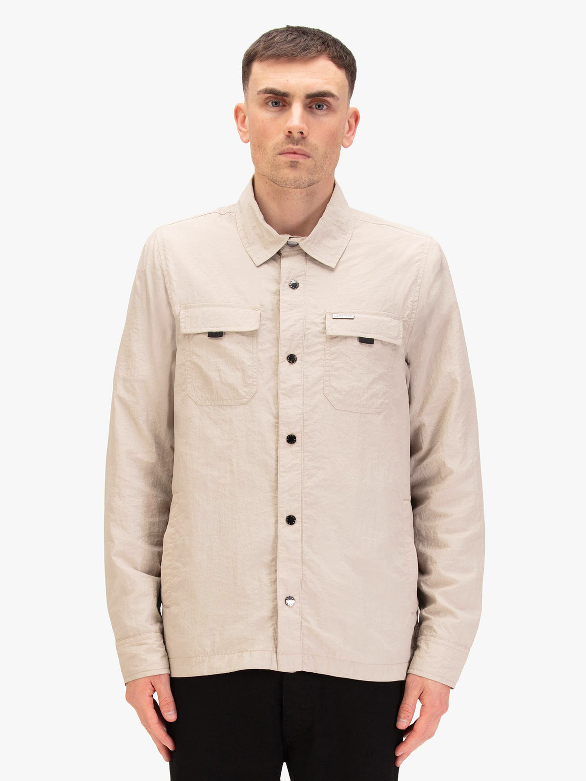 Men's beige jacket with button-up front and chest pocket, worn by a model, front view