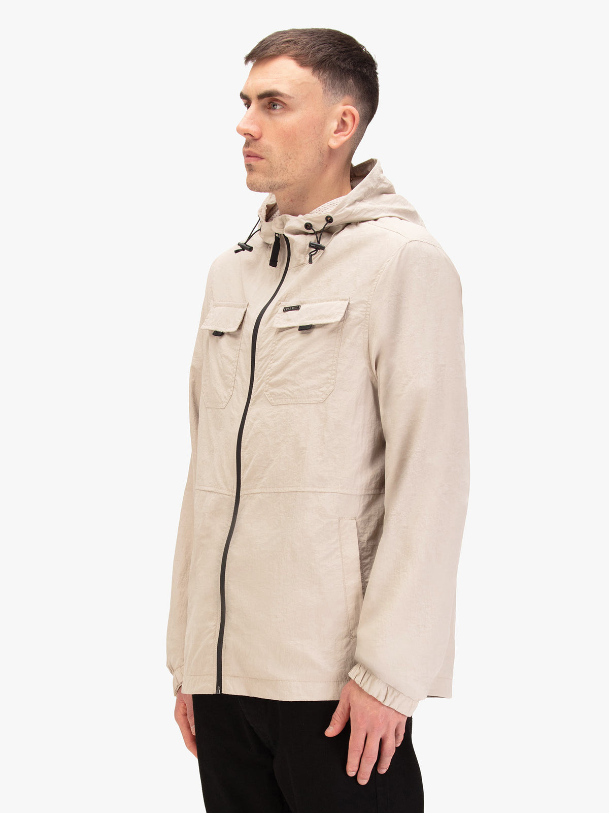 Men's beige jacket with chest pocket, worn by a model, side view
