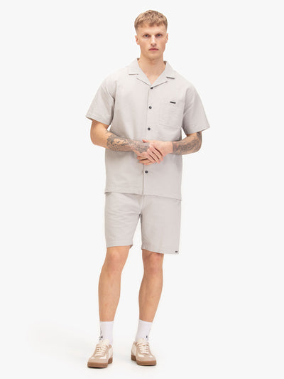Men's grey short set with short-sleeve button-up shirt and matching shorts, worn by a model.