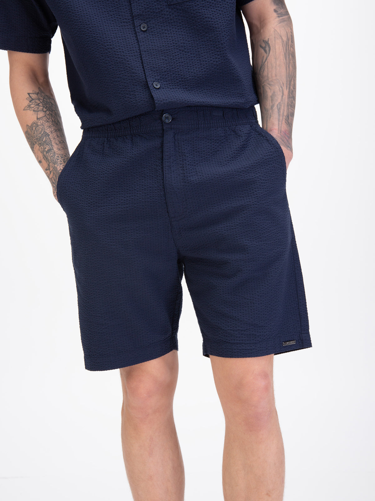 Men's navy shorts with drawstring waistband, worn by a model, detail view