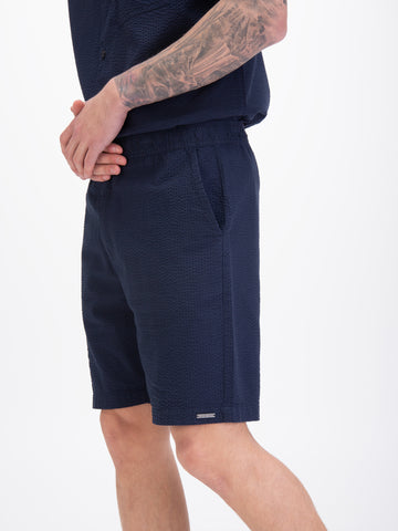 Men's navy shorts with drawstring waistband, worn by a model, detail view