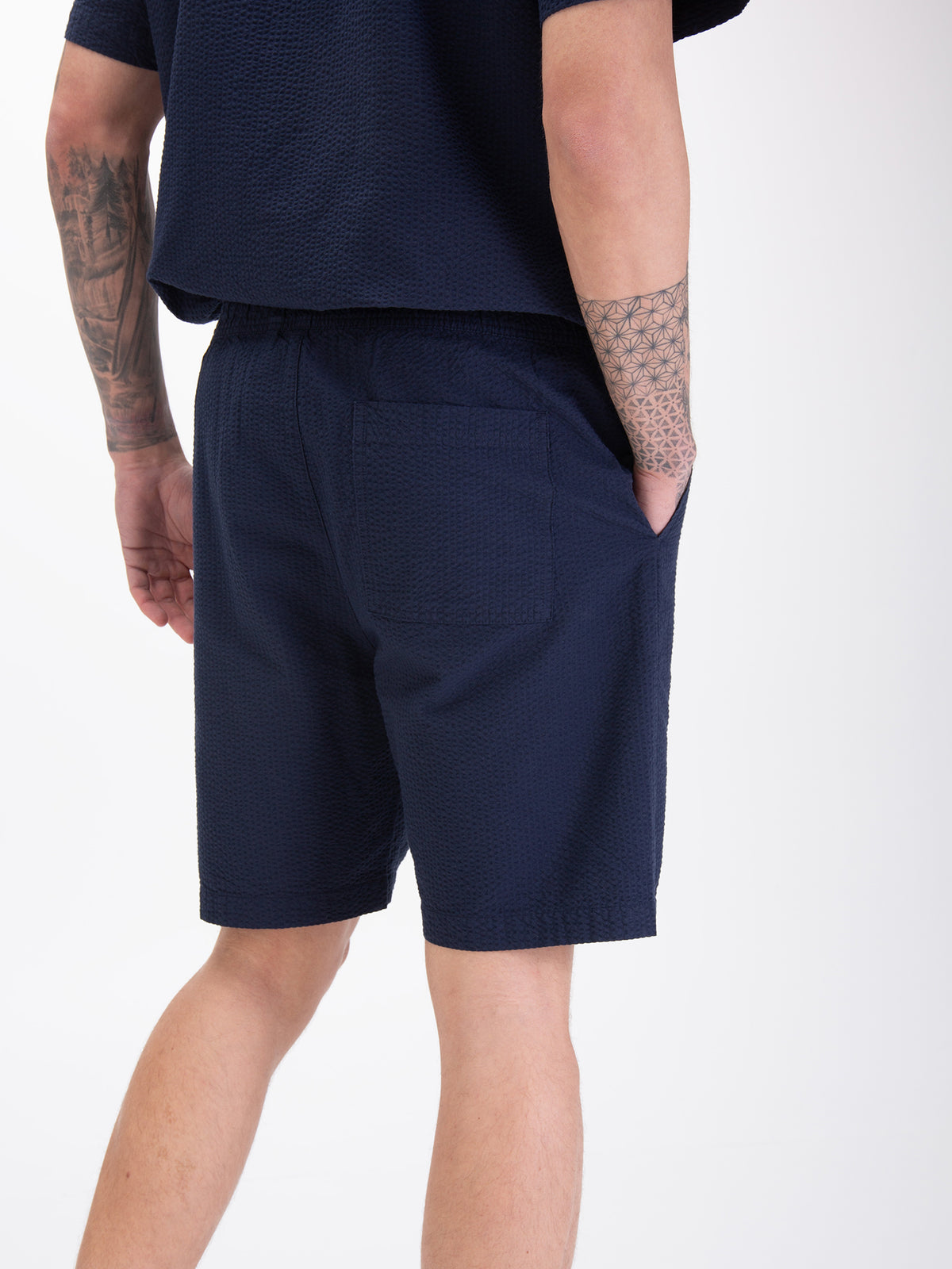 Men's navy shorts with drawstring waistband, worn by a model, detail view