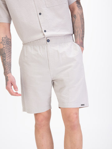 Men's grey shorts with drawstring waistband, worn by a model, detail view