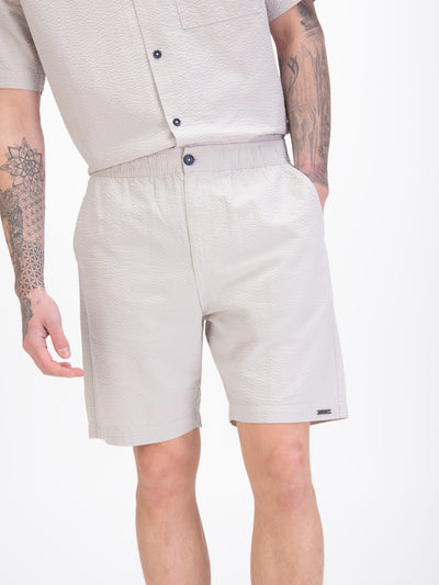 Men's grey shorts with drawstring waistband, worn by a model, detail view