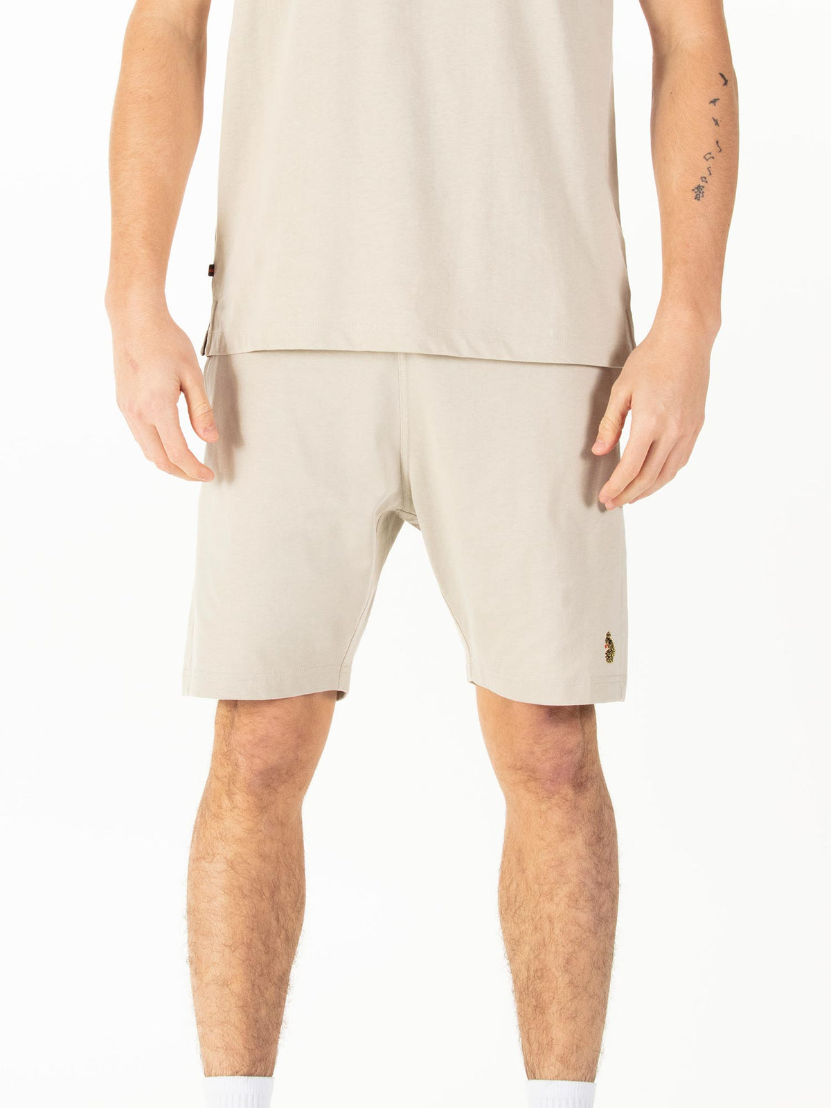 Men's beige shorts with drawstring waistband, worn by a model, front view
