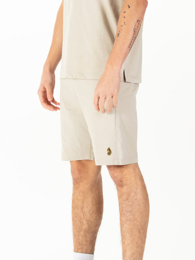 Men's beige shorts with drawstring waistband, worn by a model, side view