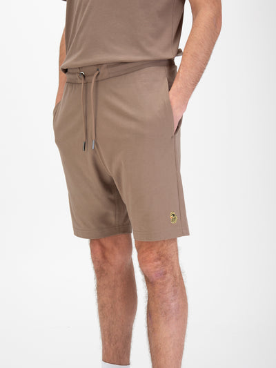 Men's brown shorts with drawstring waistband, worn by a model, detail view