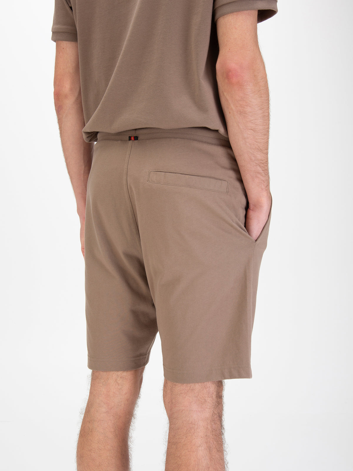Men's brown shorts with drawstring waistband, worn by a model, detail view