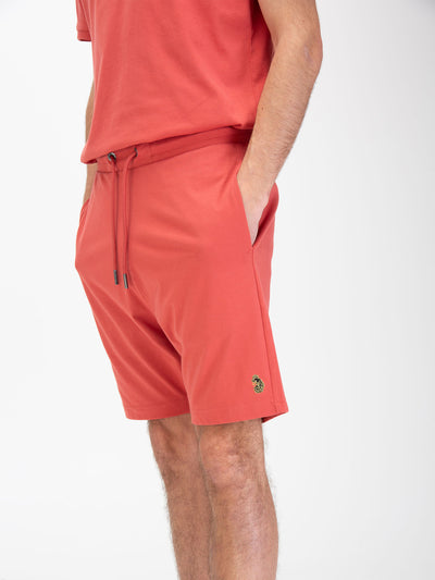 Men's red shorts with drawstring waistband, worn by a model, detail view