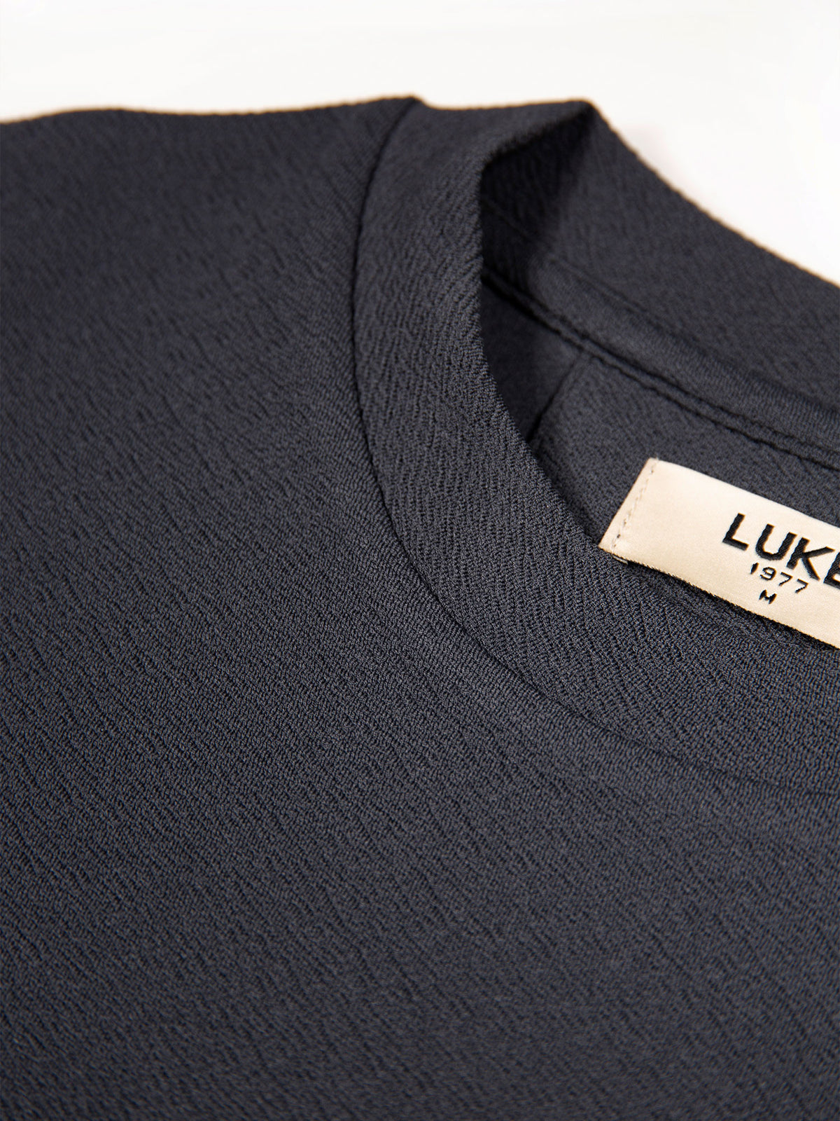Men's grey t-shirt with crew neck and short sleeves worn by a model - side view.