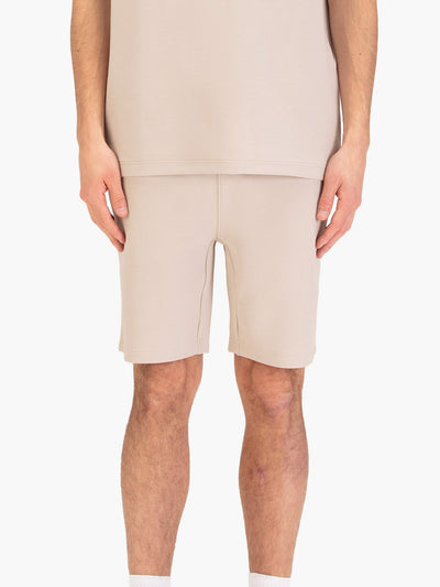 Men's beige shorts with drawstring waistband, worn by a model, front view