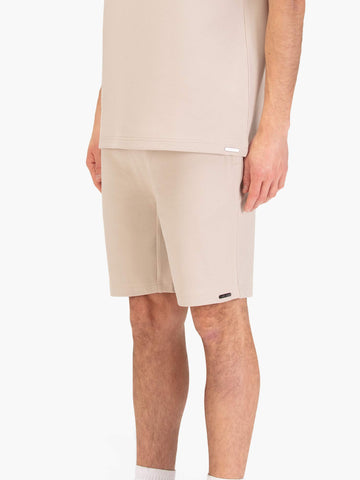 Men's beige shorts with drawstring waistband, worn by a model, side view
