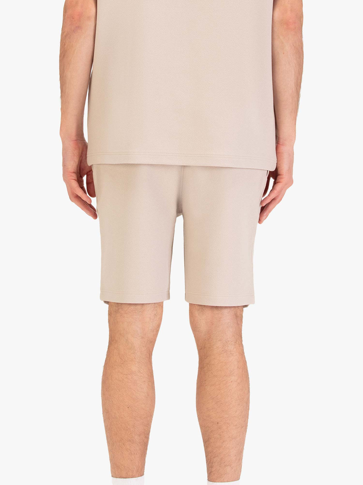 Men's beige shorts with drawstring waistband, worn by a model, back view