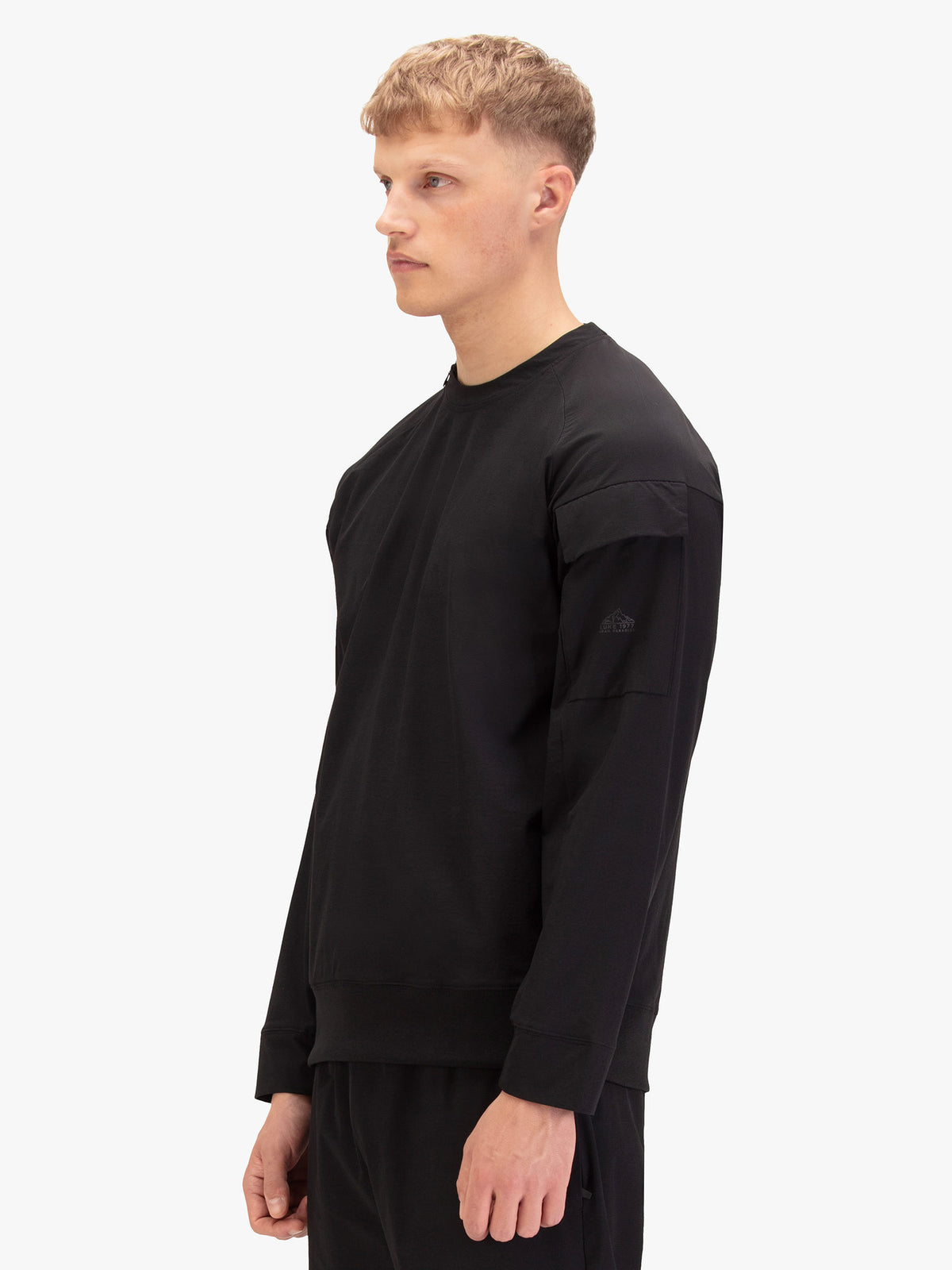 Men's black sweatshirt with crew neck, worn by a model, side view