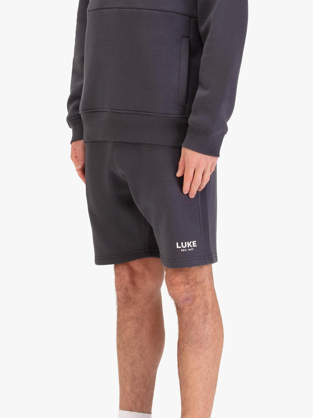 Men's grey shorts with drawstring waistband, worn by a model, side view