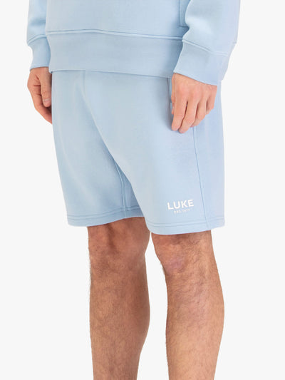 Men's blue shorts with drawstring waistband, worn by a model, side view
