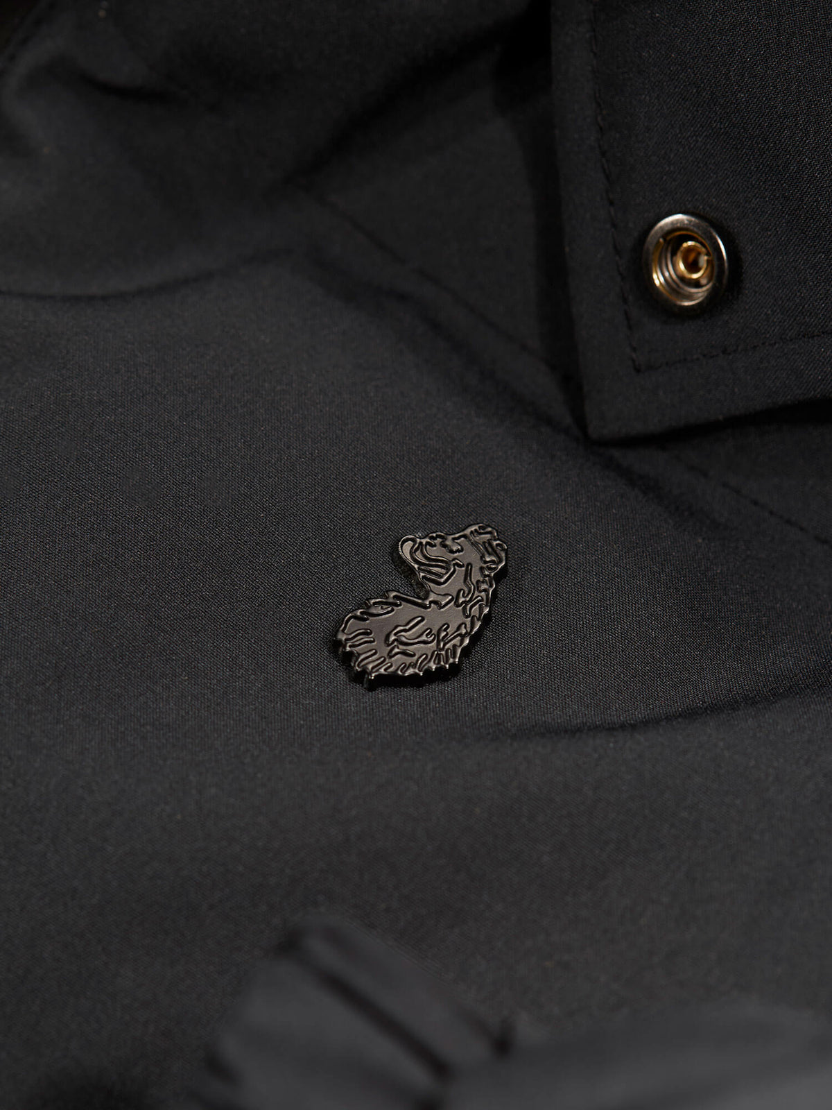 Close-up of matte black metal lion rivet and snap button on black LUKE 1977 Auckland padded jacket