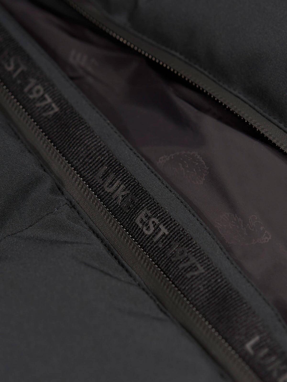 Close-up of matte zip with LUKE EST. 1977 branded tape on black LUKE 1977 Auckland padded jacket