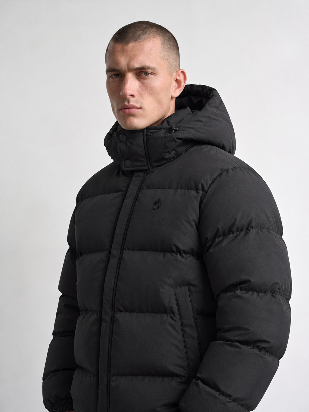 Close angled front view of man wearing black LUKE 1977 Auckland padded jacket with hood