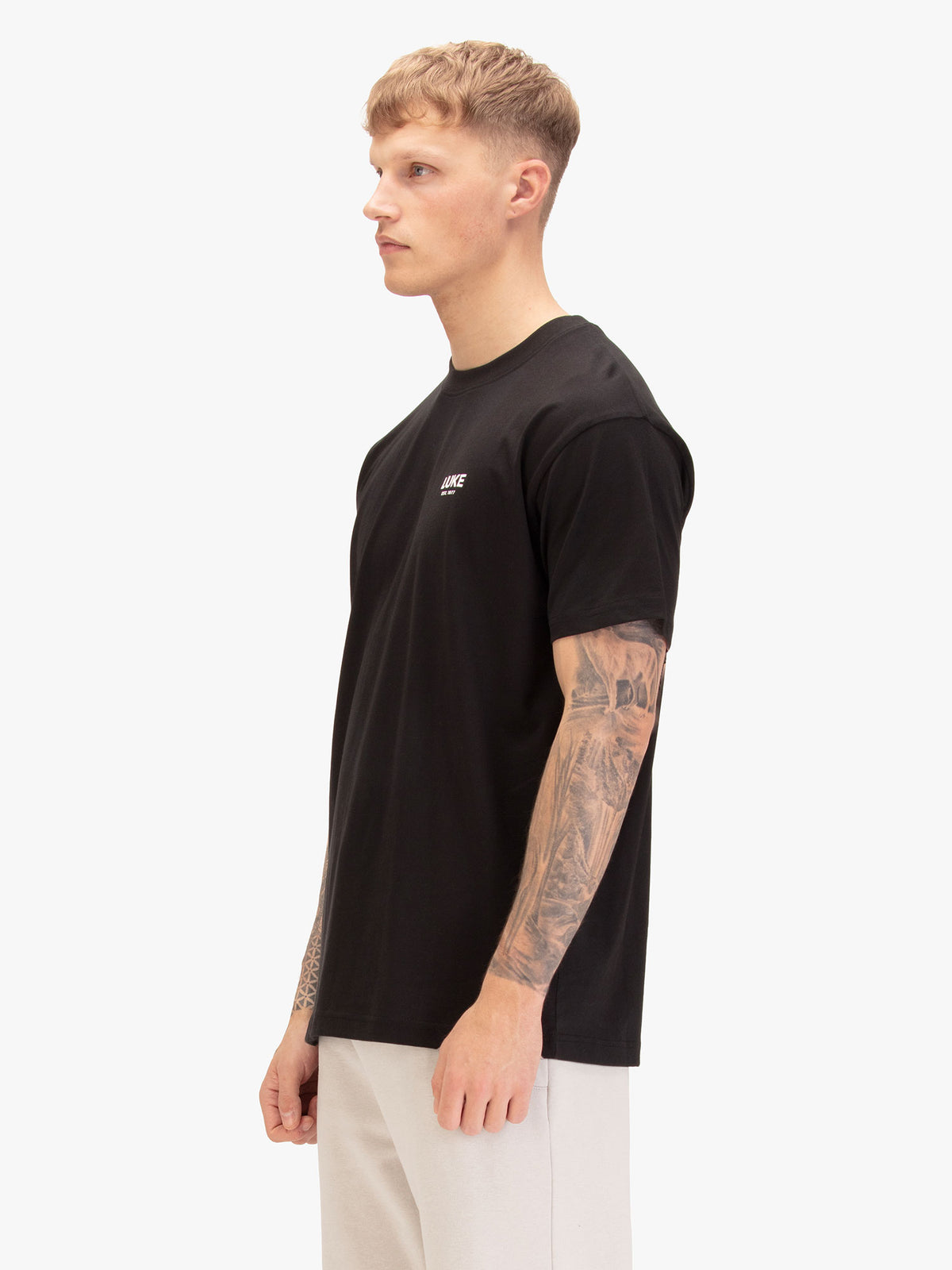 Men's relaxed-fit black t-shirt with crew neck and short sleeves, worn by a model, side view