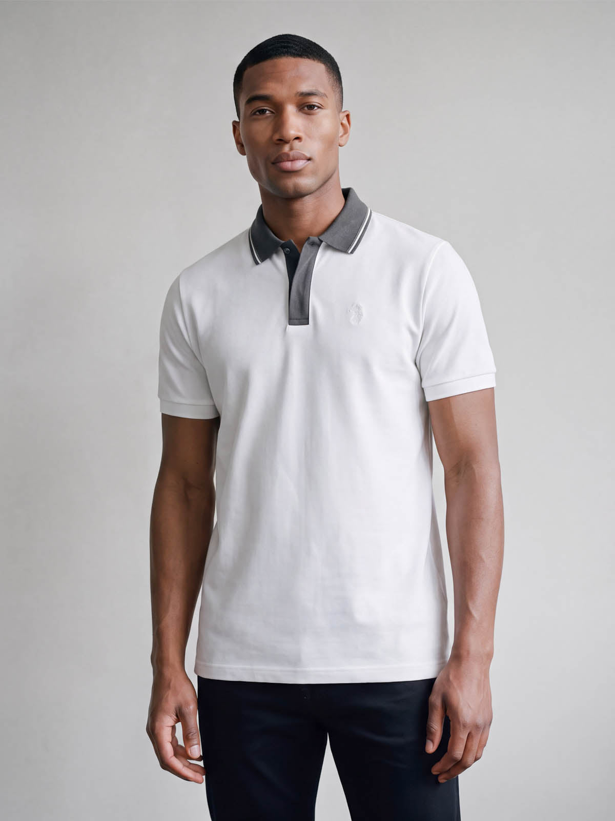 Man wearing white LUKE 1977 Leo pique polo with concrete grey collar, front view