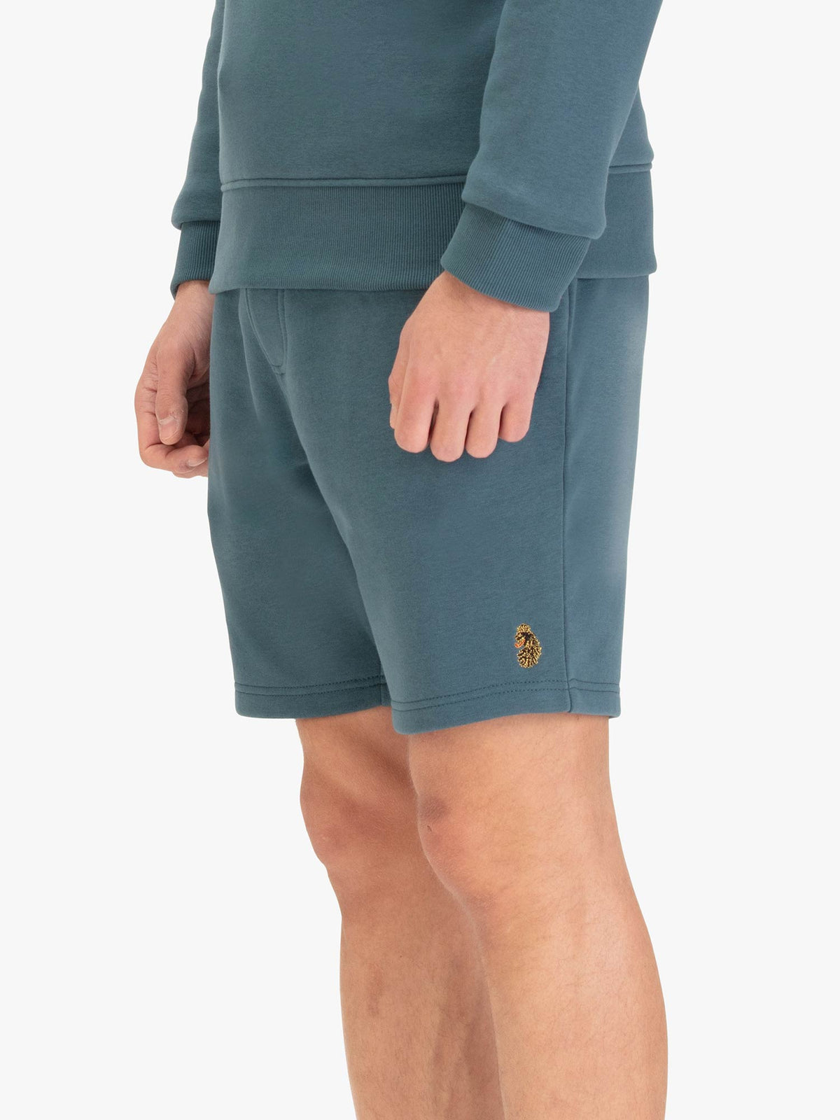 Men's blue shorts with drawstring waistband, worn by a model, side view