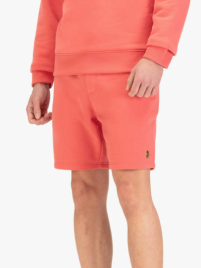 Men's red shorts with drawstring waistband, worn by a model, front view