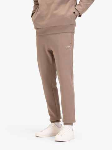 Men's brown joggers with drawstring waistband, worn by a model, front view