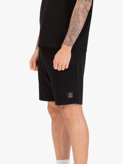 Men's black shorts with drawstring waistband, worn by a model, side view