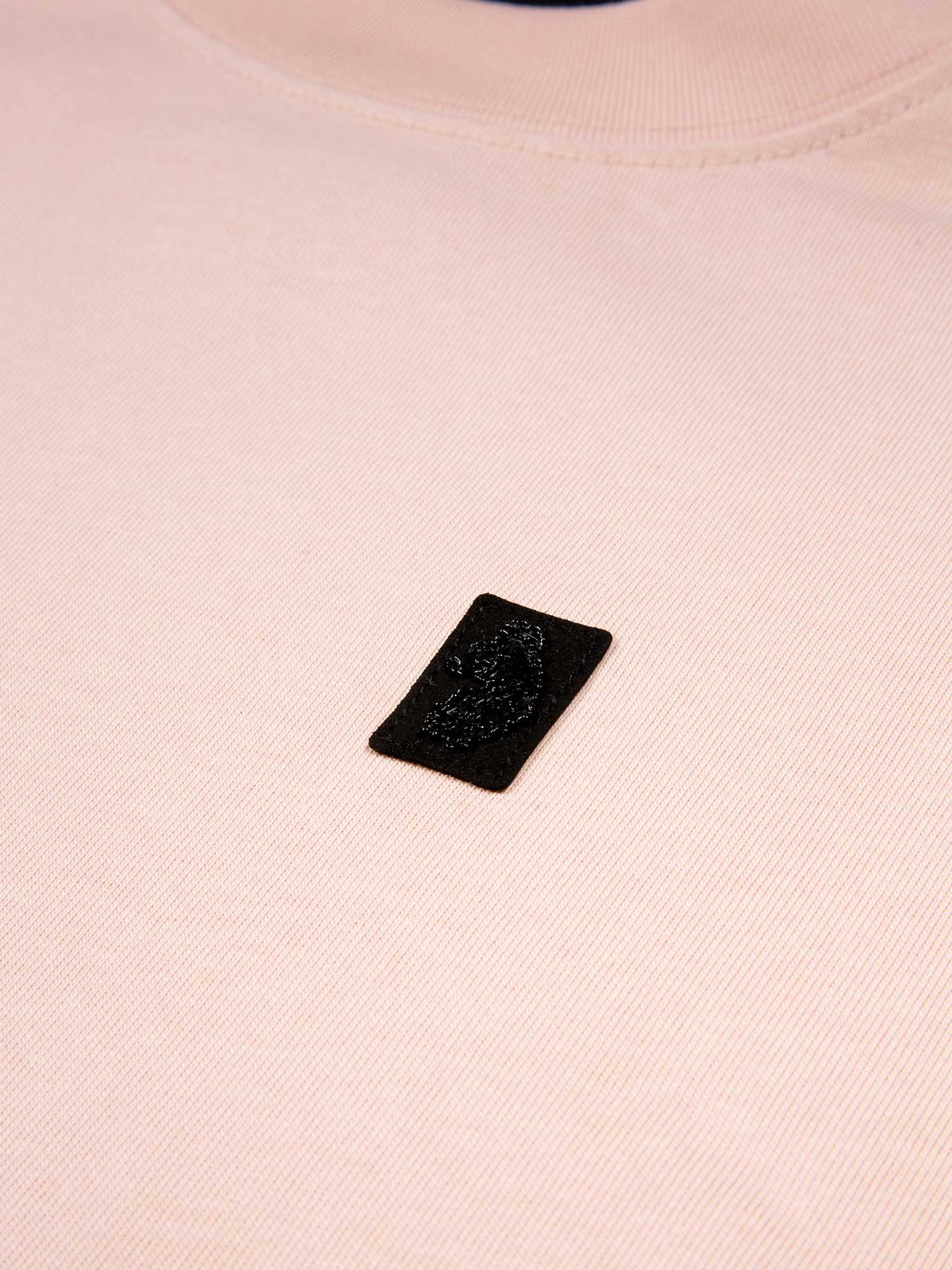 Close-up of a pink t-shirt with a black label on a light pink background