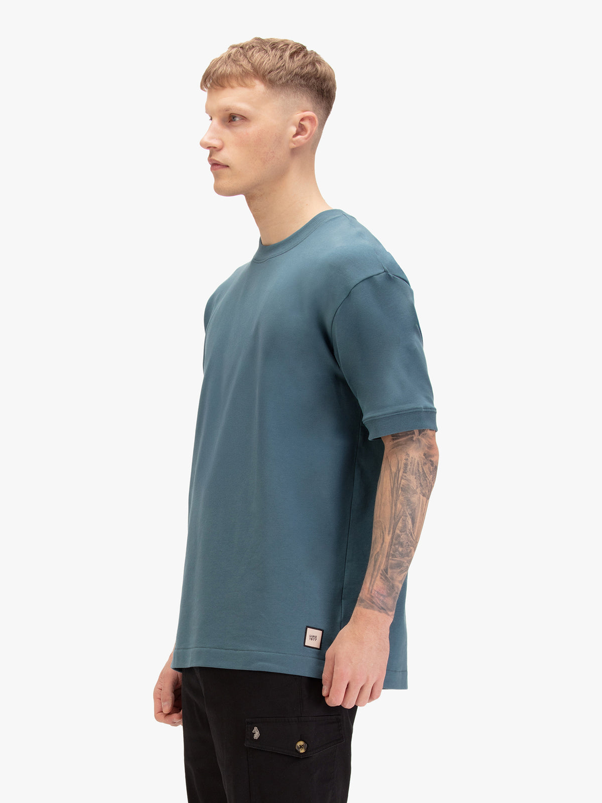 Men's relaxed-fit blue t-shirt with crew neck and short sleeves, worn by a model, side view
