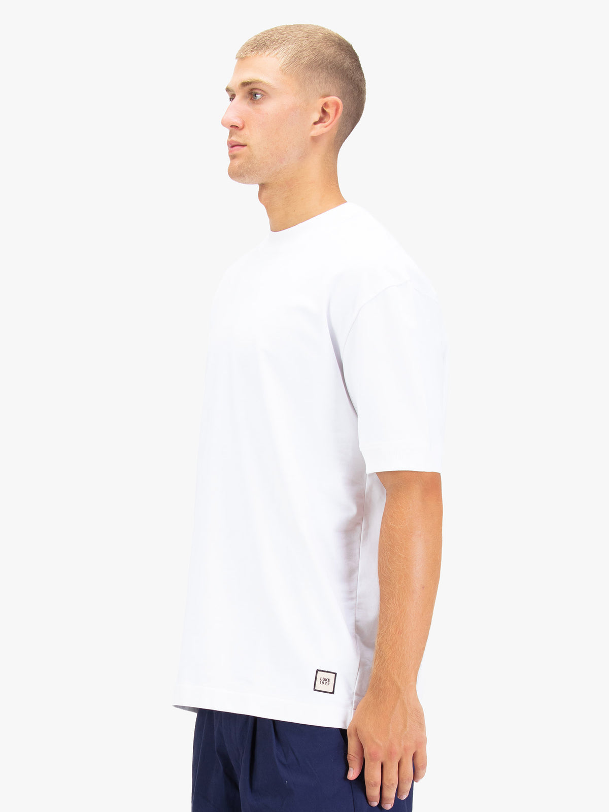 Men's white t-shirt with crew neck and short sleeves worn by a model - side view.
