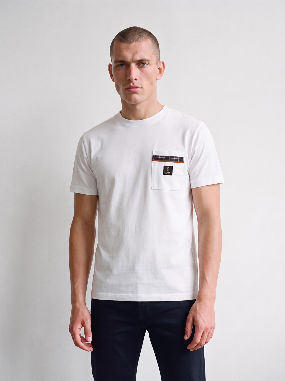 Man wearing white LUKE 1977 Kirk check pocket t-shirt with dark trousers, front view