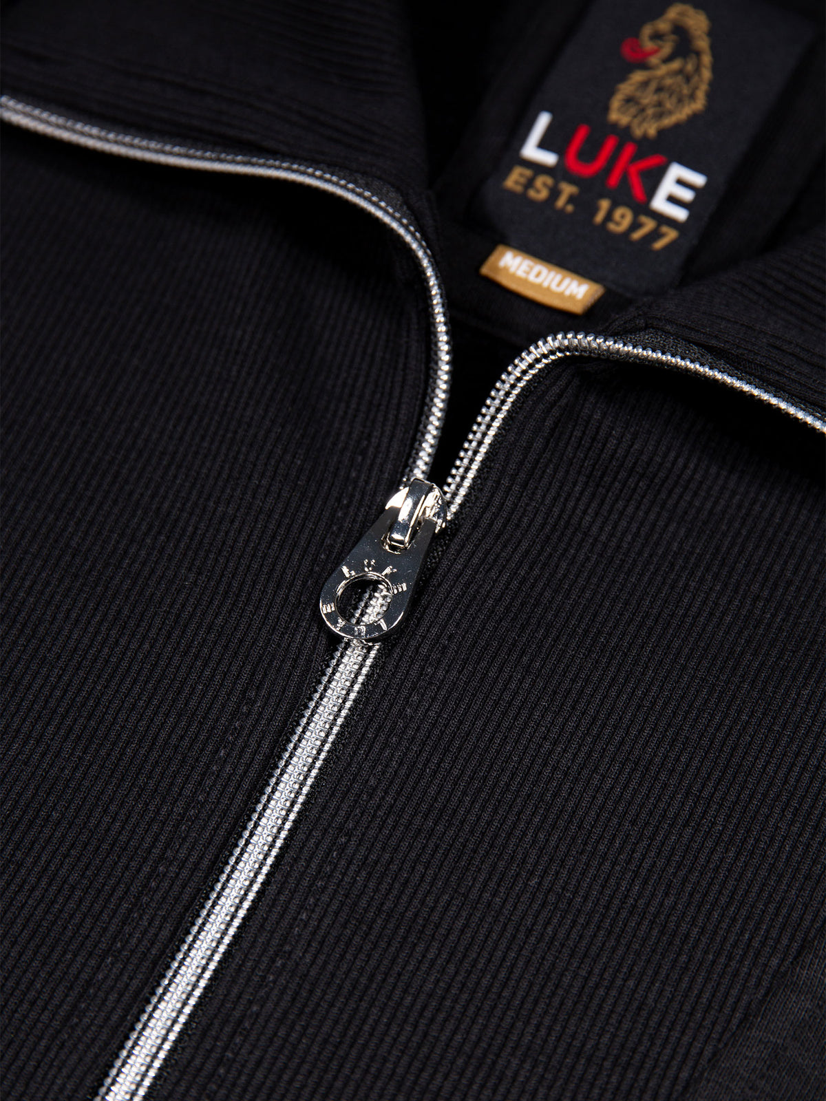 Close-up of zip collar and LUKE neck label on black Jan Jose sweatshirt