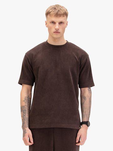 Men's relaxed-fit brown t-shirt with crew neck and short sleeves, worn by a model, side view