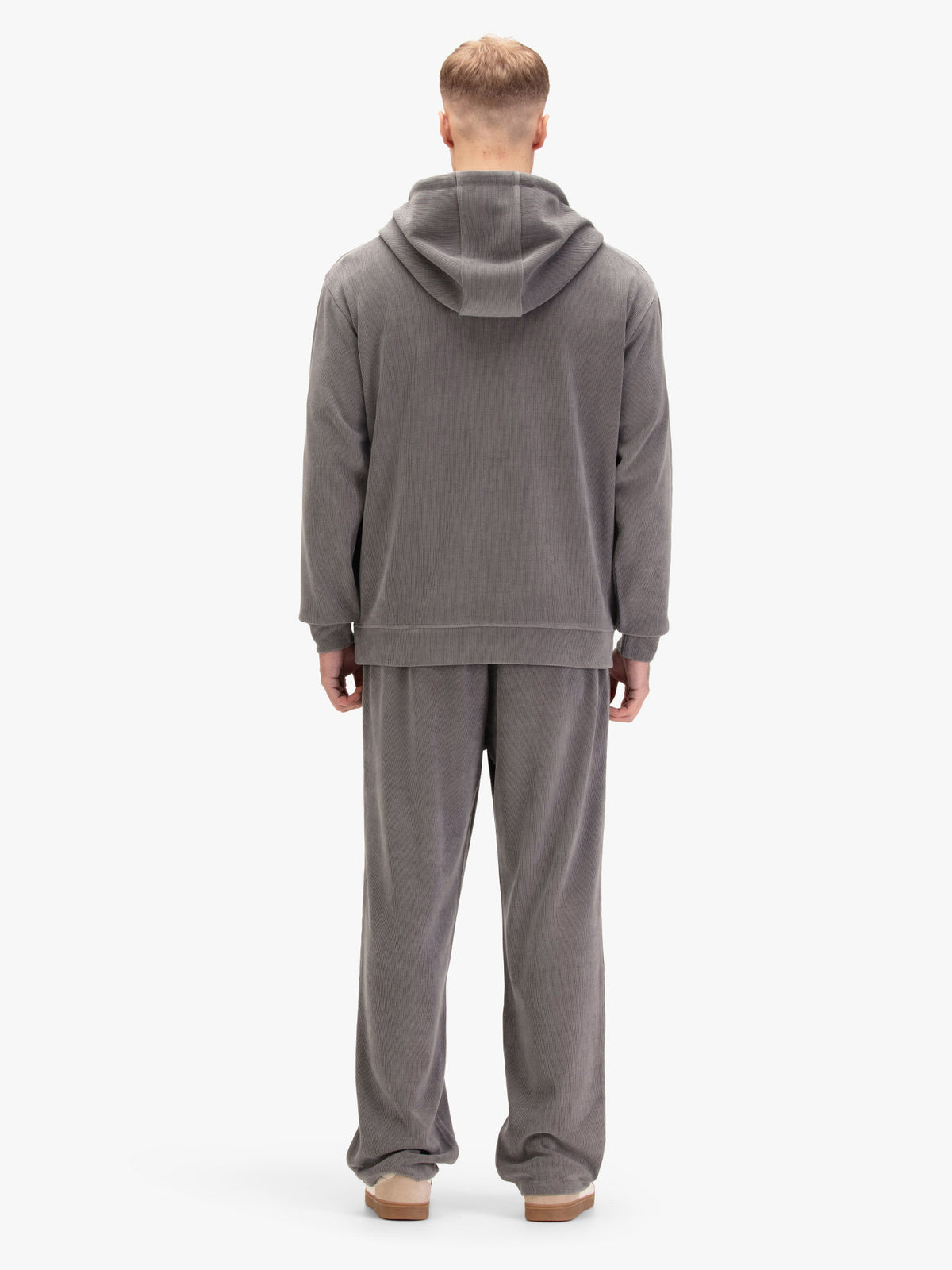 Men's relaxed-fit grey tracksuit with pullover hoodie and matching joggers, worn by a model, back view.