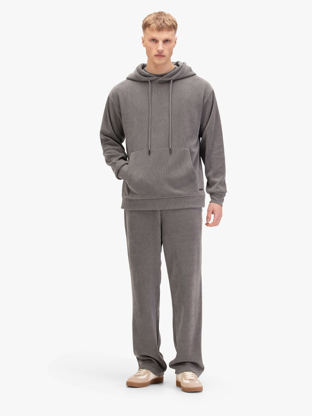 Men's relaxed-fit grey tracksuit with pullover hoodie and matching joggers, worn by model.