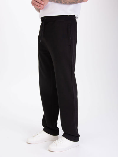 Men's wide-leg black joggers with drawstring waistband, worn by a model, detail view
