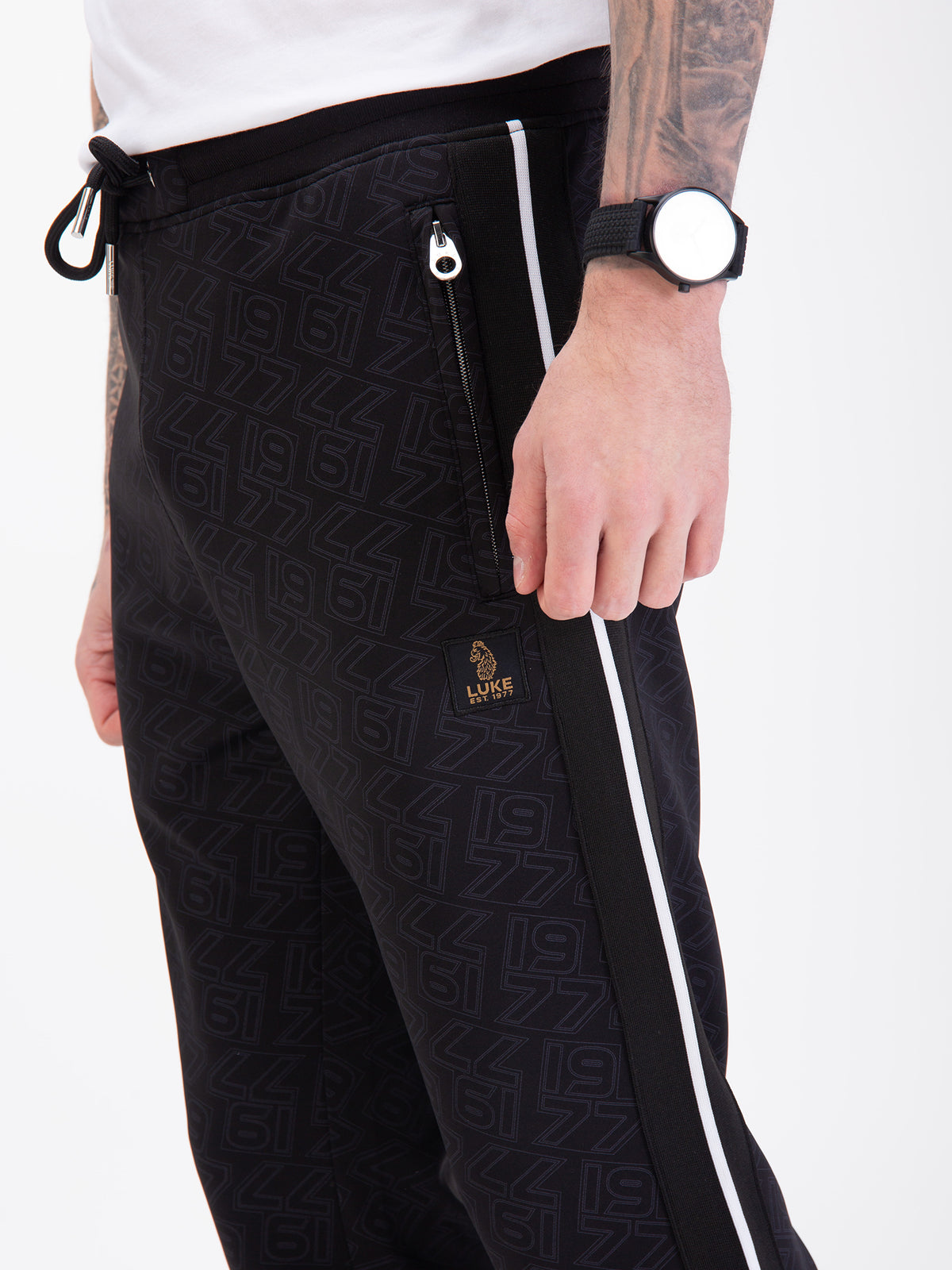 Men's black joggers with drawstring waistband, worn by a model, detail view