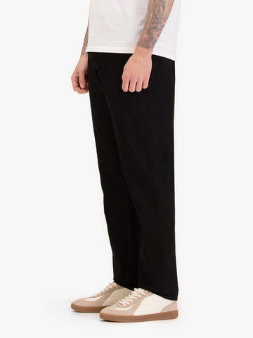 Men's straight-leg black trousers, worn by a model, side view